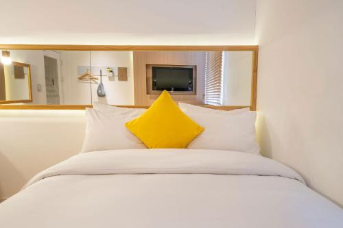 a white bed with a yellow pillow on it at Chuncheon Bom Stay in Chuncheon