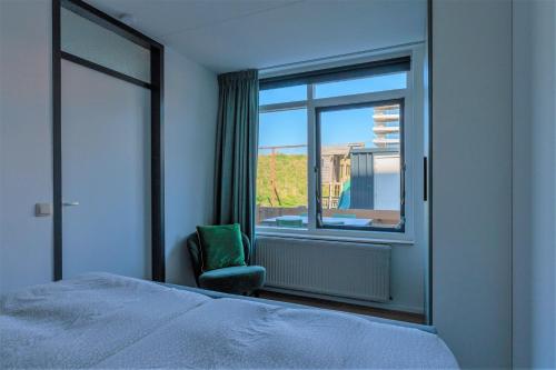 ein Schlafzimmer mit einem Bett, einem Fenster und einem Stuhl in der Unterkunft CasaMare in Egmond aan Zee