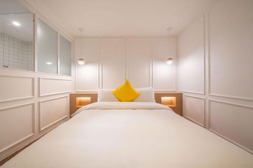 a bedroom with a large white bed with a yellow pillow at Chuncheon Bom Stay in Chuncheon