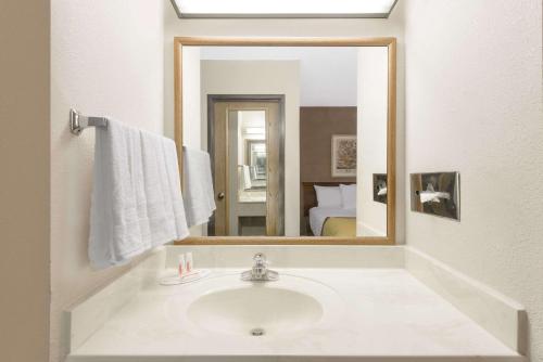 ein Bad mit einem Waschbecken und einem Spiegel in der Unterkunft Baymont by Wyndham Zanesville in Zanesville