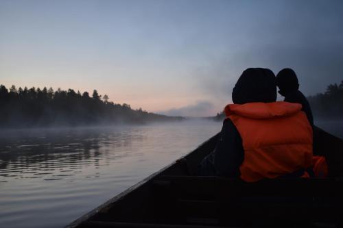 a man and a woman in a canoe on a lake at Lemmenjoen Lumo - Nature Experience & Accommodation in Lemmenjoki