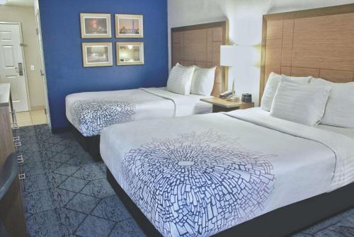 two beds in a hotel room with blue walls at La Quinta by Wyndham NE Long Beach/Cypress in Hawaiian Gardens