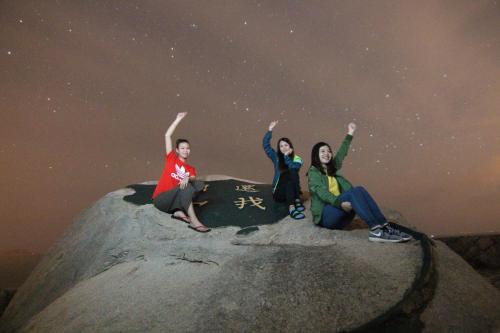 three people sitting on a rock under the stars at B&B of Blueshine in Beigan