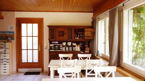 ein Esszimmer mit einem Tisch, Stühlen und Fenstern in der Unterkunft Adventure Guesthouse Interlaken in Interlaken