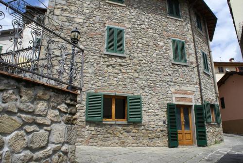 un antiguo edificio de piedra con persianas verdes y una puerta en Casa Poli Bolzoni, en San Marcello Pistoiese