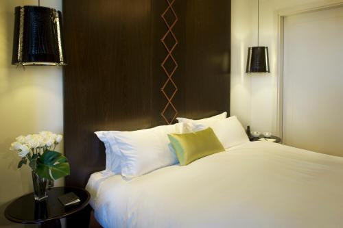 a white bed with white pillows and a vase of flowers at Sofitel Montevideo Casino Carrasco & Spa in Montevideo