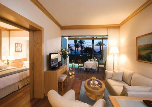 a living room with a bed and a living room with a couch at Constantinou Bros Asimina Suites Hotel in Paphos City