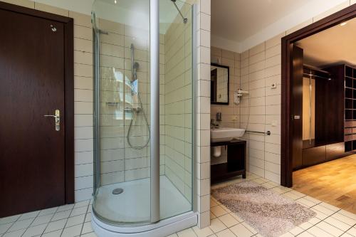 ein Bad mit einer Dusche und einem Waschbecken in der Unterkunft Apartamentai Tylios pušys in Palanga