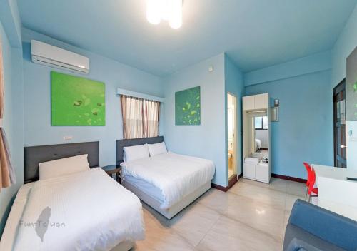 a blue bedroom with two beds and a desk and a table at Kinmen Line In Bed and Breakfast in Jinhu