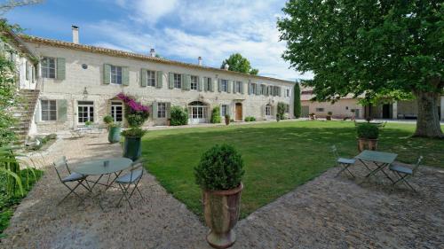 un edificio con una mesa y sillas en un patio en HOTEL et APPARTEMENTS DOMAINE DES CLOS - Teritoria, en Beaucaire