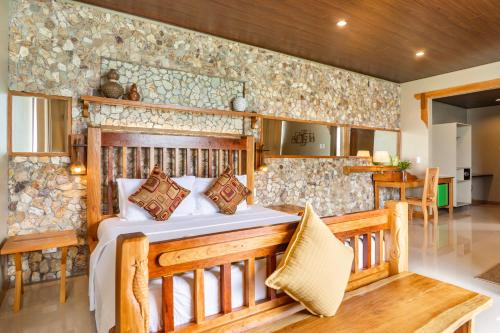 a bedroom with a bed and a stone wall at La Estancia Busuanga in Busuanga
