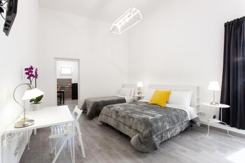 ein weißes Schlafzimmer mit 2 Betten, einem Tisch und einem Schreibtisch in der Unterkunft Il Cortile Degli Artisti in Marsala