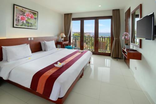 a bedroom with a large bed and a balcony at Bali Relaxing Resort and Spa in Nusa Dua