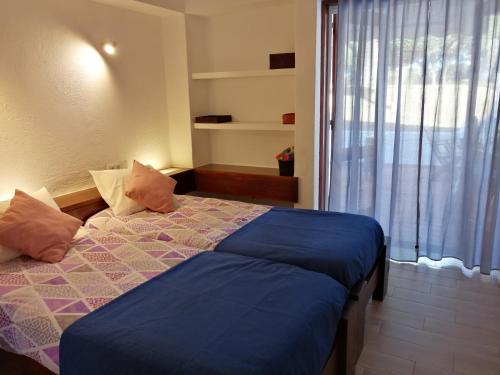 a bedroom with a bed with a blue comforter and a window at Apartamento Passarinhos in Albufeira