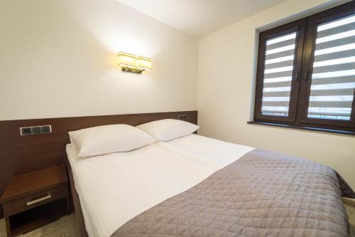 a bedroom with a white bed and a window at Willa Kormoran - Pokoje i Apartamenty in Mikołajki
