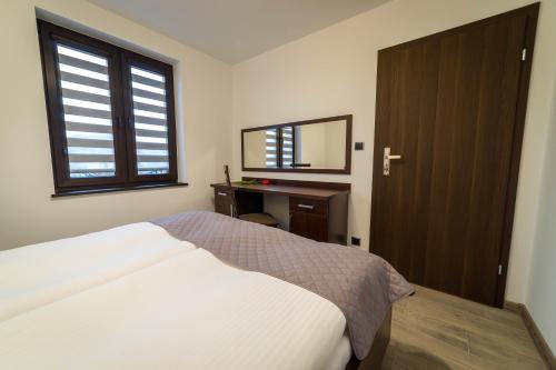 a bedroom with a bed and a desk and a mirror at Willa Kormoran - Pokoje i Apartamenty in Mikołajki