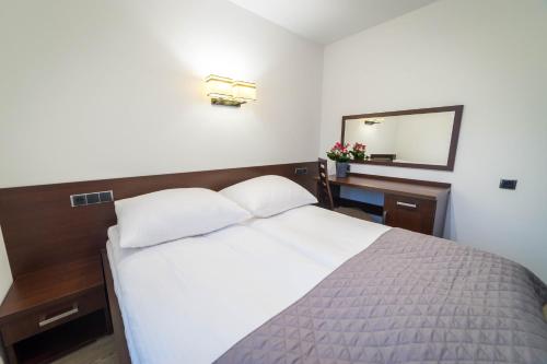 a bedroom with a white bed and a mirror at Willa Kormoran - Pokoje i Apartamenty in Mikołajki