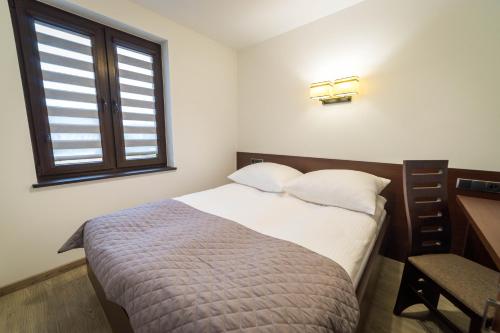 a small bedroom with a bed and a window at Willa Kormoran - Pokoje i Apartamenty in Mikołajki