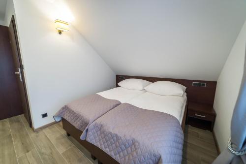 a small bedroom with a bed in a room at Willa Kormoran - Pokoje i Apartamenty in Mikołajki