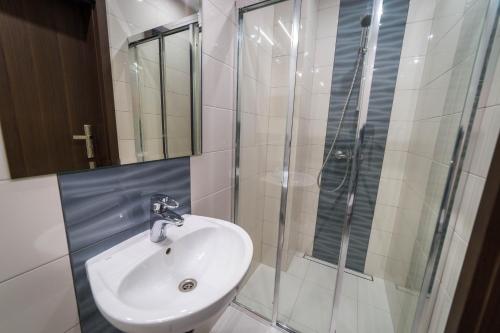 a bathroom with a sink and a shower at Willa Kormoran - Pokoje i Apartamenty in Mikołajki