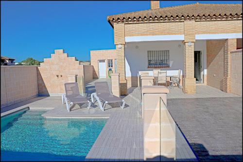 una piscina con sedie e tavolo e una casa di Chalet Peñuelas con piscina a Conil de la Frontera