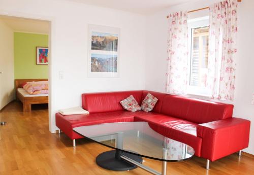 un divano rosso in soggiorno con tavolo in vetro di Villa Donautal a Inzigkofen