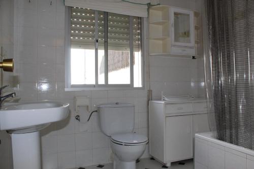 a bathroom with a toilet and a sink and a window at Casa Nieves in Ronda