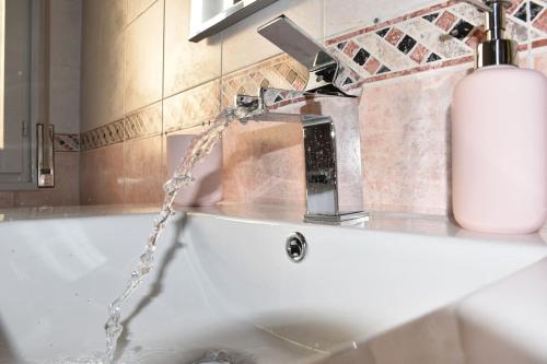 Un lavabo de baño con agua saliendo de un grifo. en The Engineer's House_Museo Enzo Ferrari, en Módena