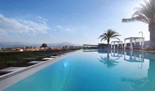 - une piscine d'eau bleue avec des palmiers dans l'établissement Quellenhof Luxury Resort Lazise, à Lazise