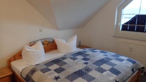 a bedroom with a checkered bed with a window at Gästehaus Siebert in Lobbe