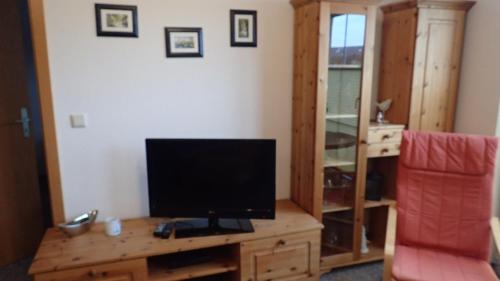 a living room with a television on a wooden desk at Gästehaus Siebert in Lobbe