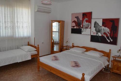 1 dormitorio con 2 camas y pinturas en la pared en Guest House Orbita, en Tyulenovo