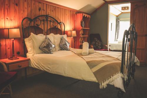 ein Schlafzimmer mit einem Bett mit einer Holzwand in der Unterkunft Biggy Best Boutique Hotel & Self Catering Cottages in Howick