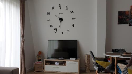 a clock on a wall above a television in a living room at Apartman Four Seasons Kopaonik in Kopaonik
