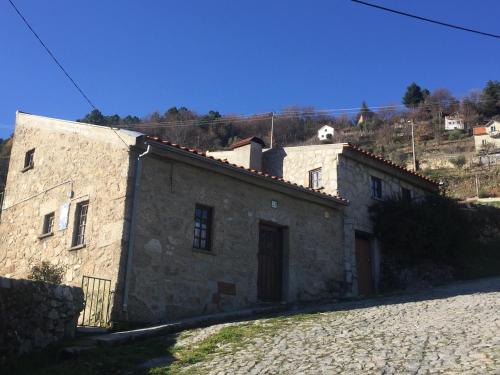 an old stone building with a hill in the background at Abrigo das Penhas in Manteigas