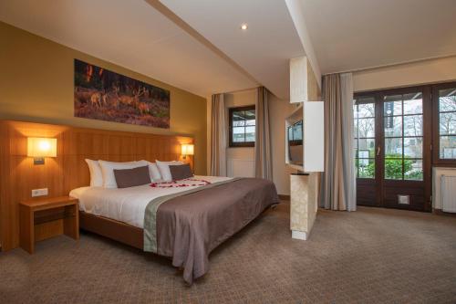 1 dormitorio grande con 1 cama grande y ventanas en Fletcher Hotel-Restaurant De Klepperman, en Hoevelaken
