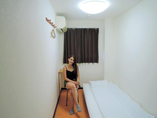 a woman sitting in a room with a bed at HOTEL LUCKY / Vacation STAY 3952 in Osaka