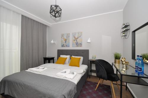 a bedroom with a bed with yellow pillows and a desk at Apartament RESORT Chełmońskiego Śrem in Śrem