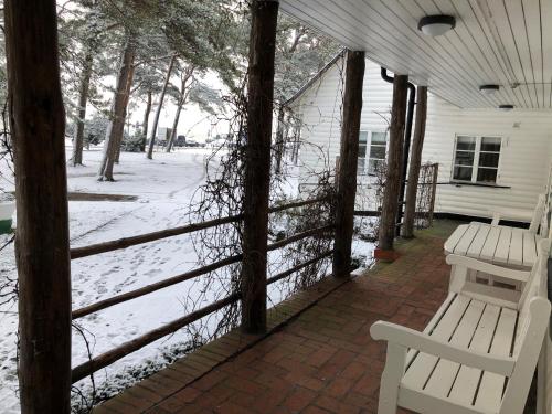 two white benches sitting on a porch in the snow at EFS Höllviksstrand in Höllviken