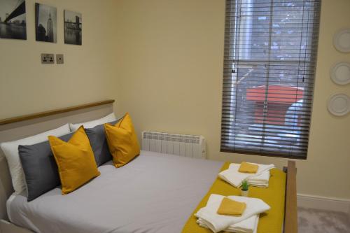 OnPoint - 2 Bed Apartment City Centre Ideal Location! في نوتينغهام: غرفة نوم بسرير ومخدات صفراء ونافذة