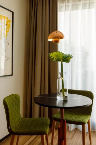 a dining room with a table and two green chairs at Protur Naisa Palma Hotel in Palma de Mallorca