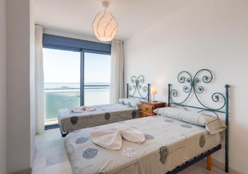 two beds in a bedroom with a view of the ocean at Apartamentos Varadero Sea View in Cala del Moral