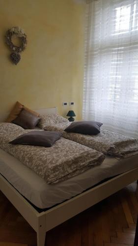 łóżko z poduszkami w pokoju z oknem w obiekcie APPARTAMENTO FRANCESCO GIUSEPPE w mieście Gossensass-Colle Isarco