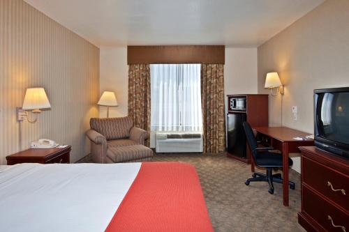 a hotel room with a bed and a desk and a television at Holiday Inn Express Hotel and Suites - Henderson by IHG in Las Vegas