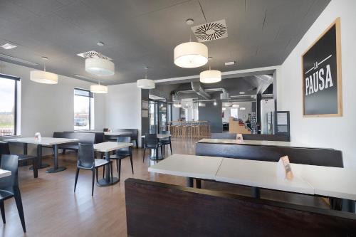 a dining room with tables and chairs and windows at AS Hoteles Ponferrada in Columbrianos