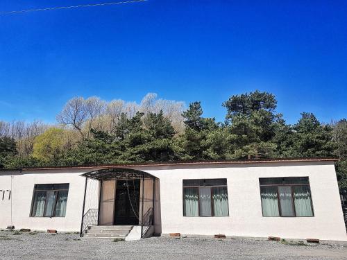 a large white building with a door and trees at Cozy Hotel Kazbegi in Stepantsminda