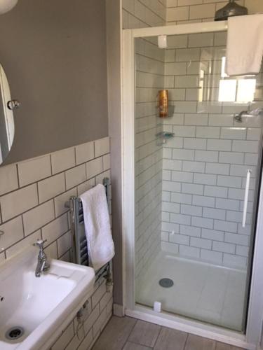 a white bathroom with a shower and a sink at Home Farm House in Wimborne Saint Giles