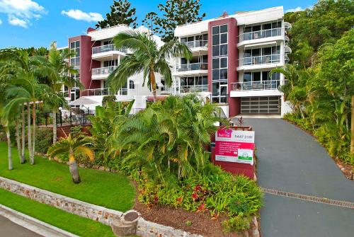 an apartment complex with palm trees and a driveway at Bali Hai Apartments Noosa in Noosa Heads