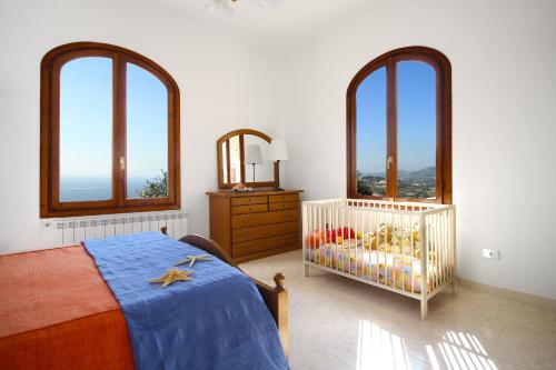 a bedroom with a crib and three windows at Appartamenti Villa Chiara in Imperia