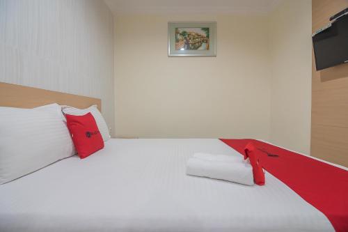 a bedroom with a white bed with red pillows at RedDoorz near MT Haryono Semarang in Semarang
